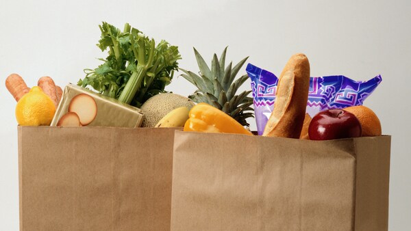 Two paper grocery bags with produce displaying from the top