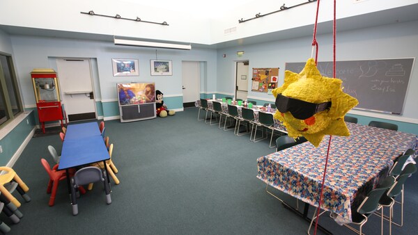 A large recreation room with long tables and sun piñata hanging from a rope
