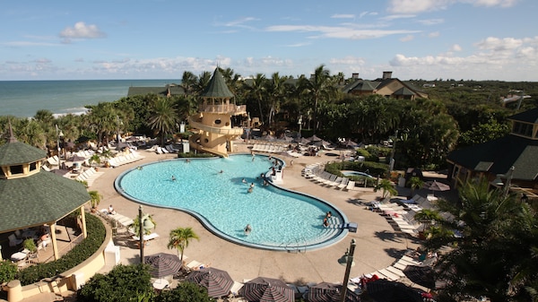 Mickey-shaped pool with waterslide, surrounded by lounge chairs
