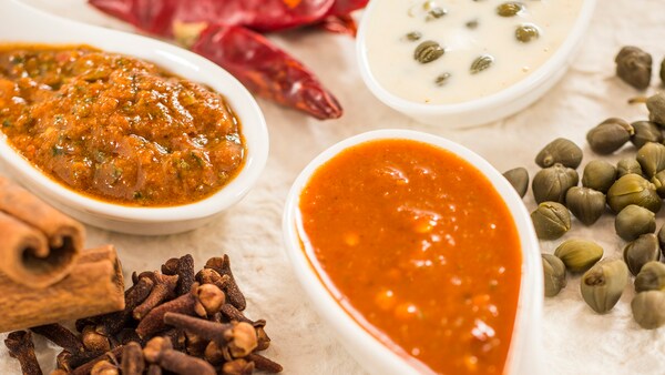 A wooden spoon stirs minestrone soup in a pot