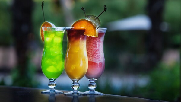 Three specialty drinks sitting on a wooden bar