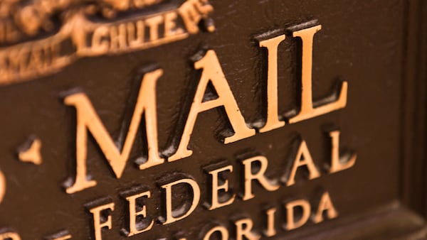 Close-up of the front of a bronze U.S. Mail chute