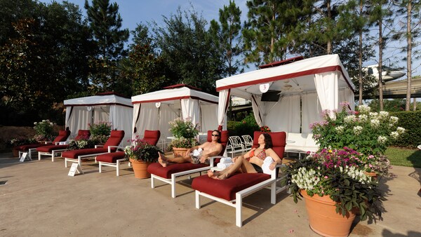 A man and woman lounge on deck chairs in front of a cabana