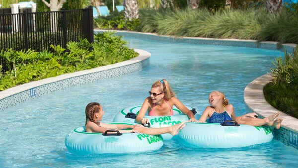 2 kids and a woman float in a tract of water on inner tubes with words that read Float Lagoon