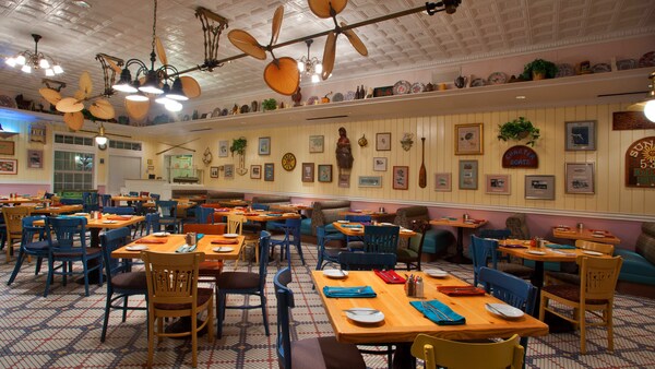 A restaurant seating area with set tables and a row of ceiling fans
