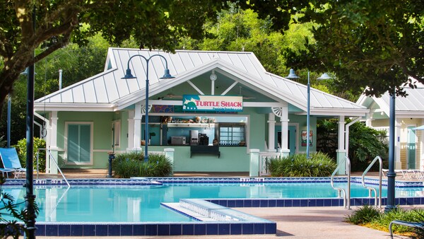 A pool near a bar with a sign that reads Turtle Shack Poolside Snacks
