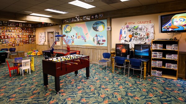 A Community Hall with foosball, video monitors, air hockey and shelves of games and toys