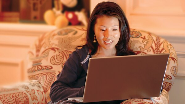 A Guest, sitting in an overstuffed chair, uses a laptop computer to search the internet