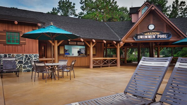 Chaises longues et table avec parasol sur un patio devant le Meadow Snack Bar