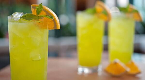 3 iced drinks adorned with an orange slice and a sprig of mint