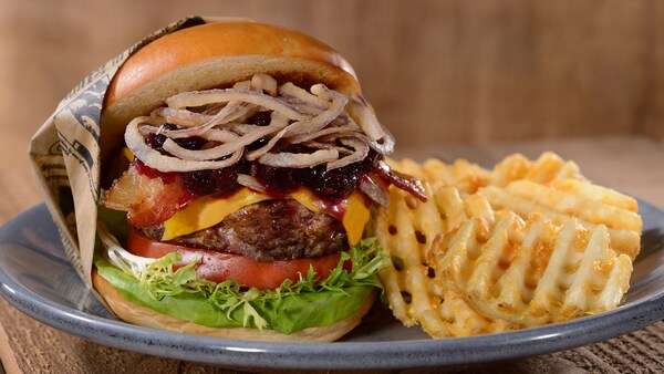 A cheeseburger topped with bacon and onions, served with waffle fries