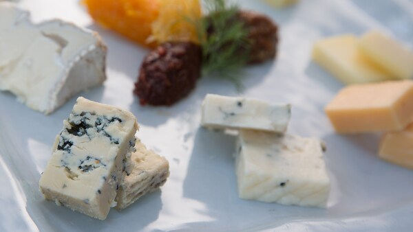 A platter topped with a variety of gourmet cheeses and sun dried tomato puree