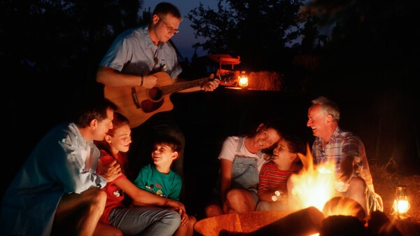 Guests enjoying a guitar player around a campfire at Disney's Fort Wilderness Resort