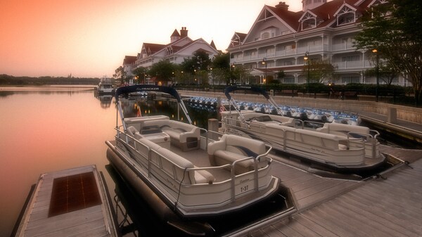 2 botes amarrados en un muelle junto a los jardines de un resort de Disney
