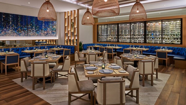 Un comedor del restaurante Amare en Walt Disney World Swan Reserve con un expositor de vinos de vidrio 