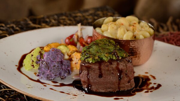 A serving of filet mignon served on a plate with macaroni and vegetables