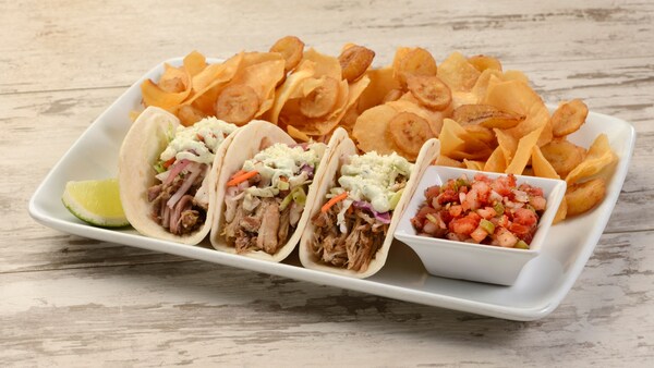 Three tacos served on a plate with salsa and yuca chips