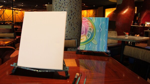 A blank canvas, paintbrushes and a painting of a turtle inside Jiko The Cooking Place