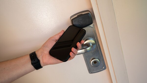 A hand holding a smartphone to a room door lock at Disney's Caribbean Beach Resort