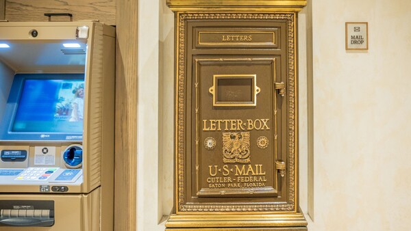A US Mail letter box next to an ATM and a sign that reads ‘Mail Drop’ at Disney’s Coronado Springs Resort