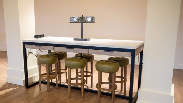 A tall table surrounded by stools and topped with a lamp