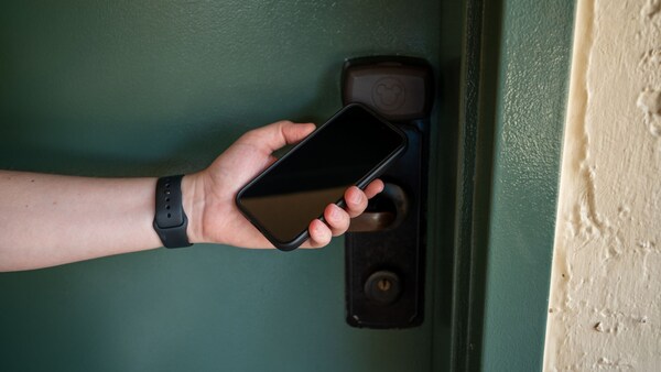A person holds a smartphone up to a hotel room door handle at Disney’s Coronado Springs Resort
