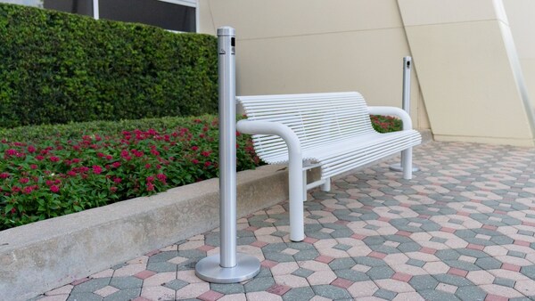 Un banc de parc moderne se trouve devant un lit de fleurs et des arbustes soignés