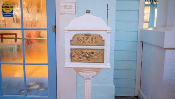 Un buzón antiguo decorativo en un atril junto a una entrada a la tienda Conch Flats General Store en Disney’s Old Key West Resort 