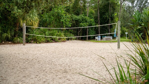A volleyball net on a sand court at Disney’s Old Key West Resort, surrounded by lush foliage