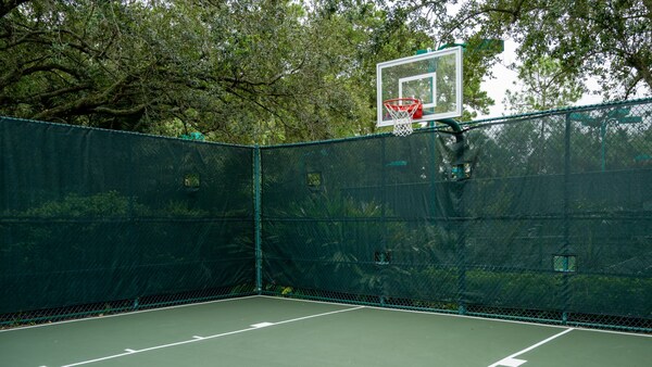An outdoor basketball court at Disney’s Old Key West Resort, surrounded by a fence and greenery