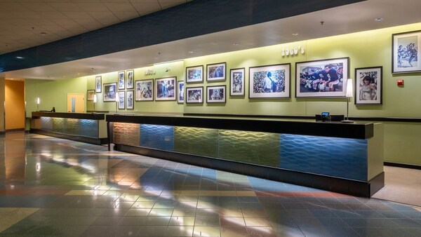 A front desk and check-in area with framed pictures of moments in sports and pop culture, divided by decade
