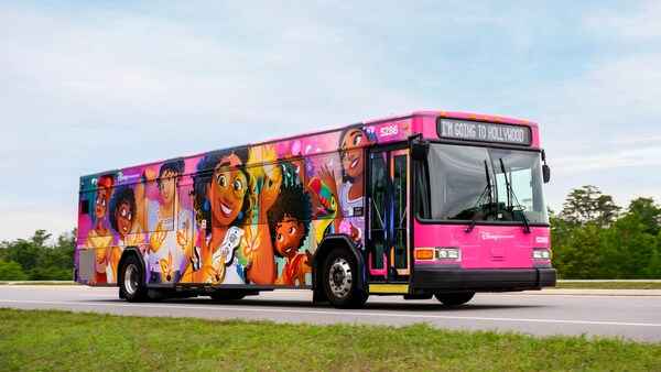 El exterior de un autobús de Walt Disney World cubierto de vibrantes obras de arte con personajes de la película Encanto