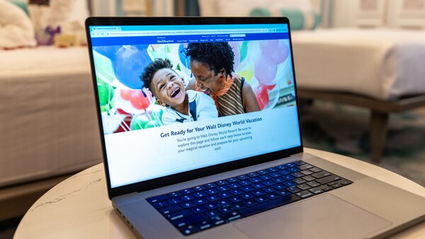 Una computadora portátil que muestra el sitio web de Walt Disney World Resort sobre la mesa en una habitación
