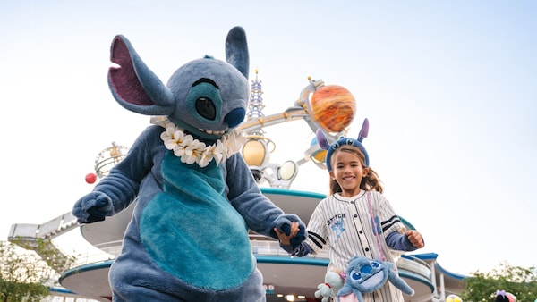Stitch holds a young girl’s hand in Tomorrowland at Magic Kingdom park
