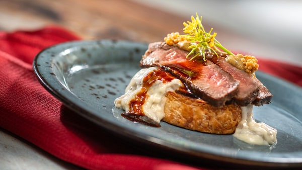 Beef Wellington inspired Croissant Supreme with creamed spinach pinwheel, mushroom gorgonzola ragout, mustard grilled flank steak, red wine sauce and pickled mustard seeds