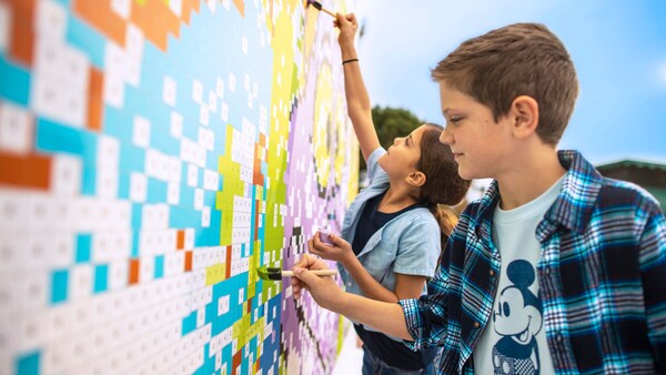 Two children painting a large image of Figment