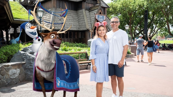 A couple posing with a Magic Shot overlay of Olaf and Sven in the Norway Pavilion at Epcot