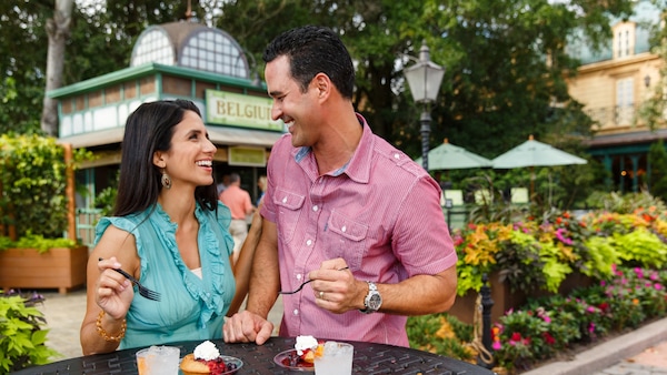 Two Guests enjoying food and drinks at the Belgium booth during the Epcot International Food & Wine Festival