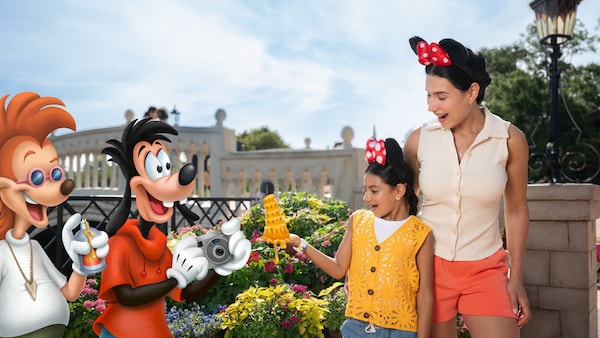 A Disney PhotoPass Magic Shot featuring 2 Guests holding the Leaning Tower of Cheeza from ‘A Goofy Movie’ while Max Goof and Bobby Zimmeruski take a picture of them in Epcot