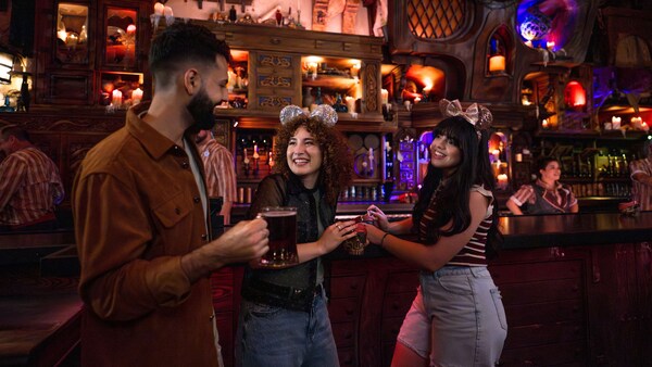Three Guests smiling and raising glasses at The Beak and Barrel tavern in Magic Kingdom park