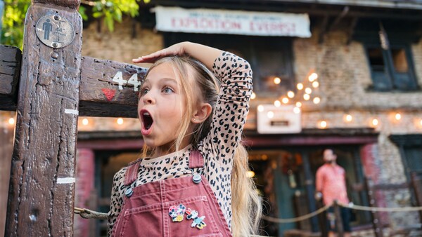 A young girl expresses shock and excitement as she clears the 44 inch height requirement at an attraction’s measuring station
