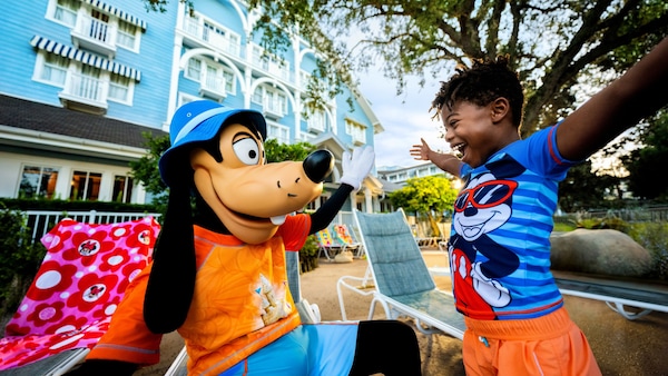 Un enfant souriant d’excitation alors qu’il salue Goofy près de la piscine au Disney’s Beach Club Resort.