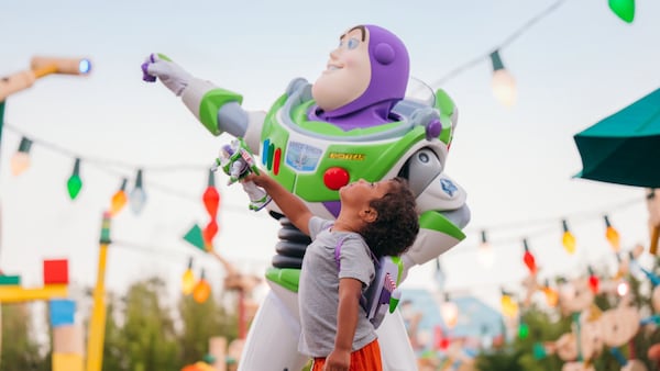 A boy standing next to Buzz Lightyear in Toy Story Land