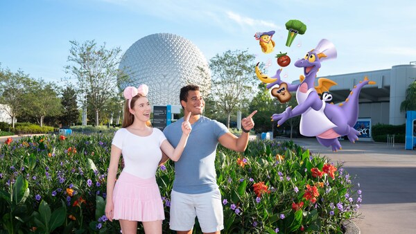A couple posing with an augmented reality overlay of Chef Figment in front of Spaceship Earth at Epcot
