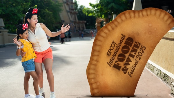A Disney PhotoPass Magic Shot featuring 2 Guests looking at a giant empanada with text that reads ‘Epcot International Food and Wine Festival Twenty Twenty Five’