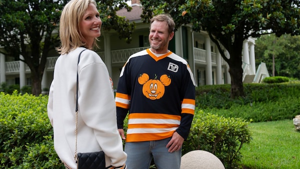 2 Guests smiling outdoors while wearing Halloween themed Disney apparel