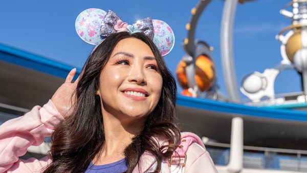 A Guest wearing a Minnie Mouse ear headband featuring Lilo and Stitch