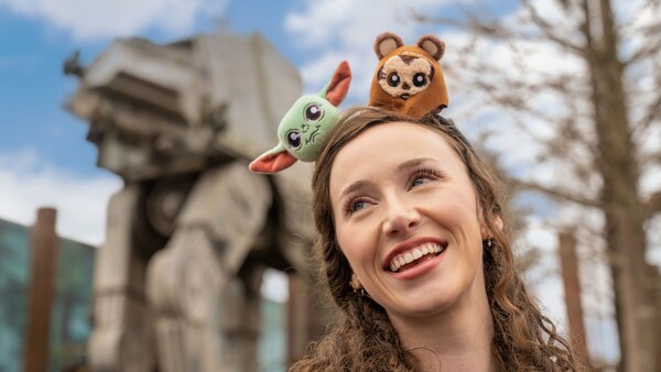 A Guest wearing a Star Wars themed Mickey Mouse ear headband while smiling near Star Tours The Adventures Continue at Disney's Hollywood Studios theme park