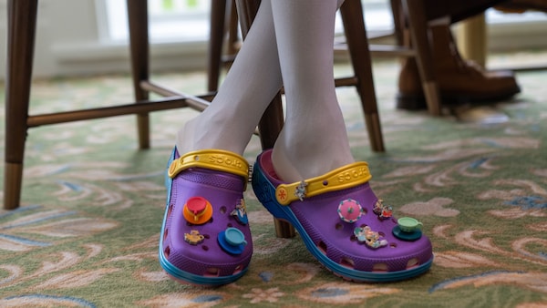 A Guest wearing a pair of Crocs decorated with colorful charms inspired by Alice in Wonderland