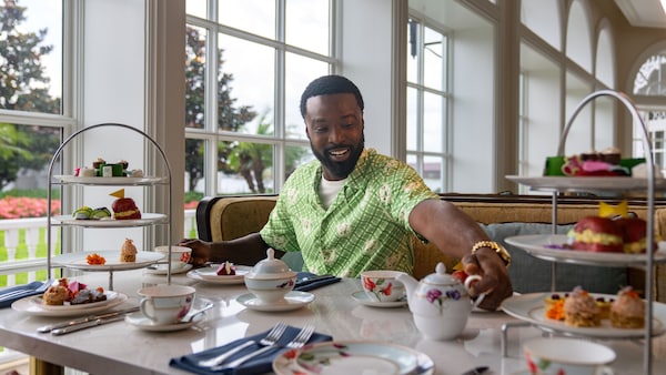 A Guest enjoys afternoon tea with tiered trays of pastries at The Garden View Lounge Tea Experience